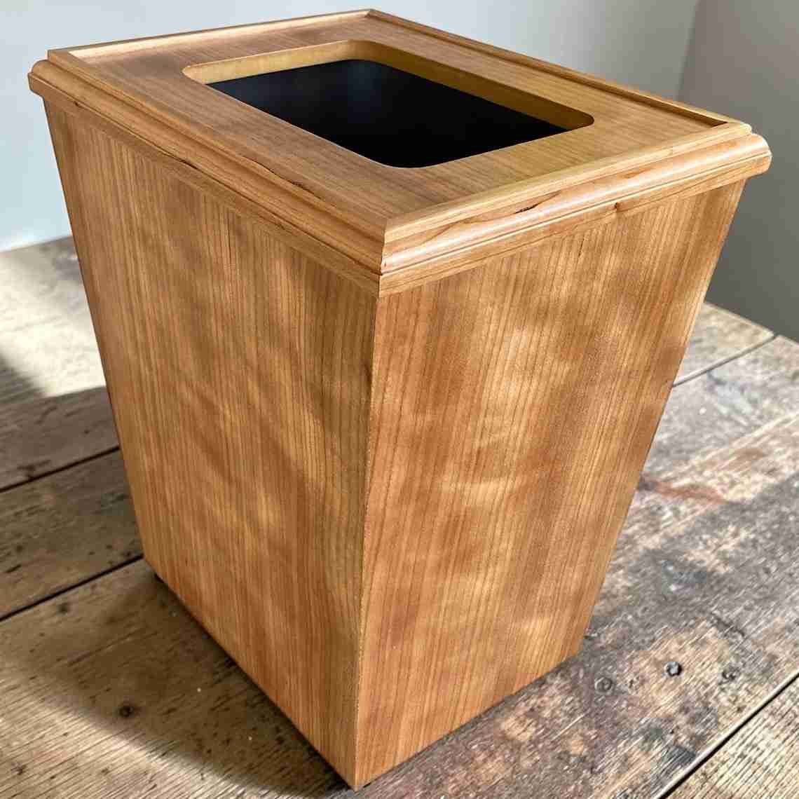 Cherry veneer wooden waste bin with a rectangular top opening and black interior.